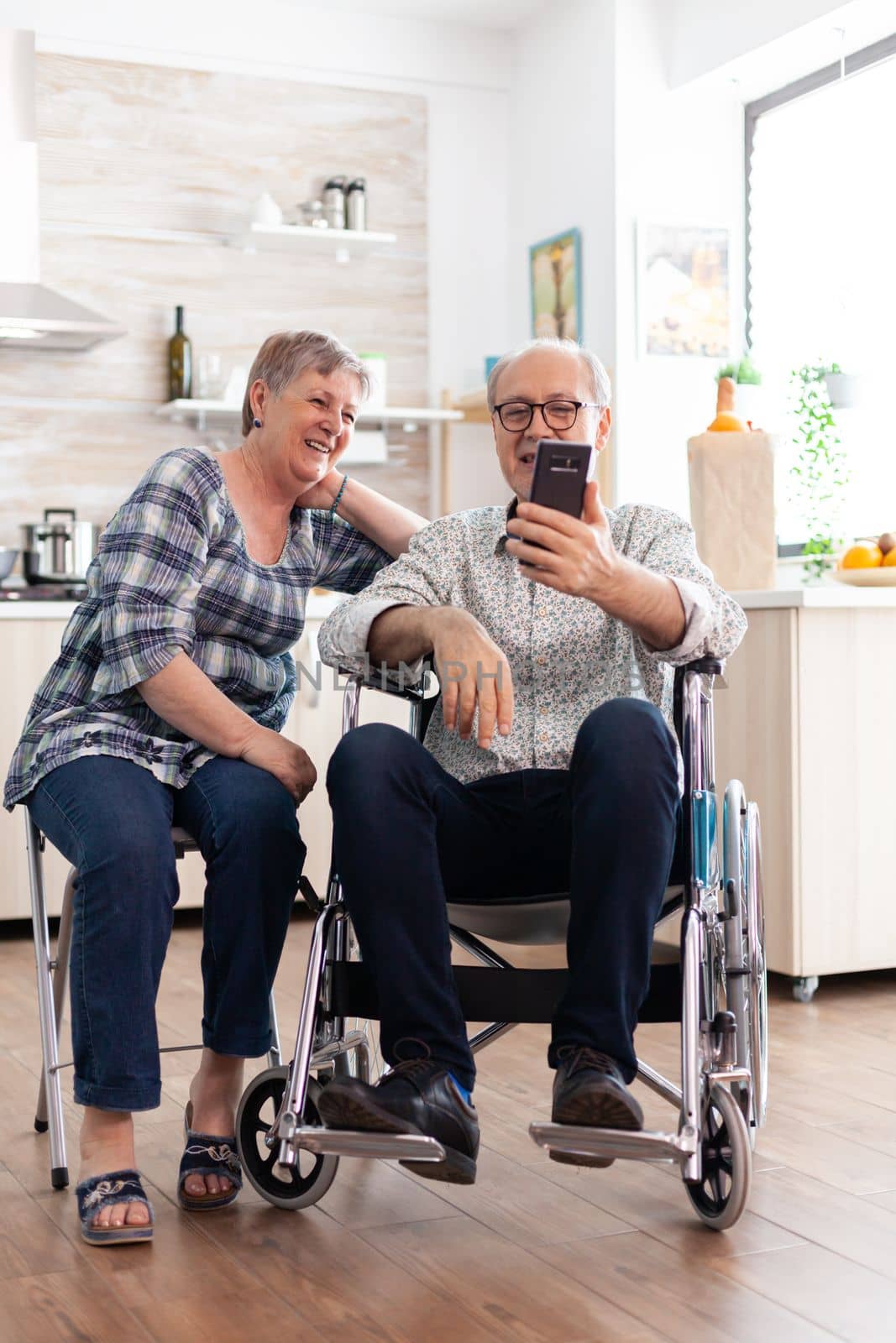 Smiling disabled man and his wife using smartphone by DCStudio