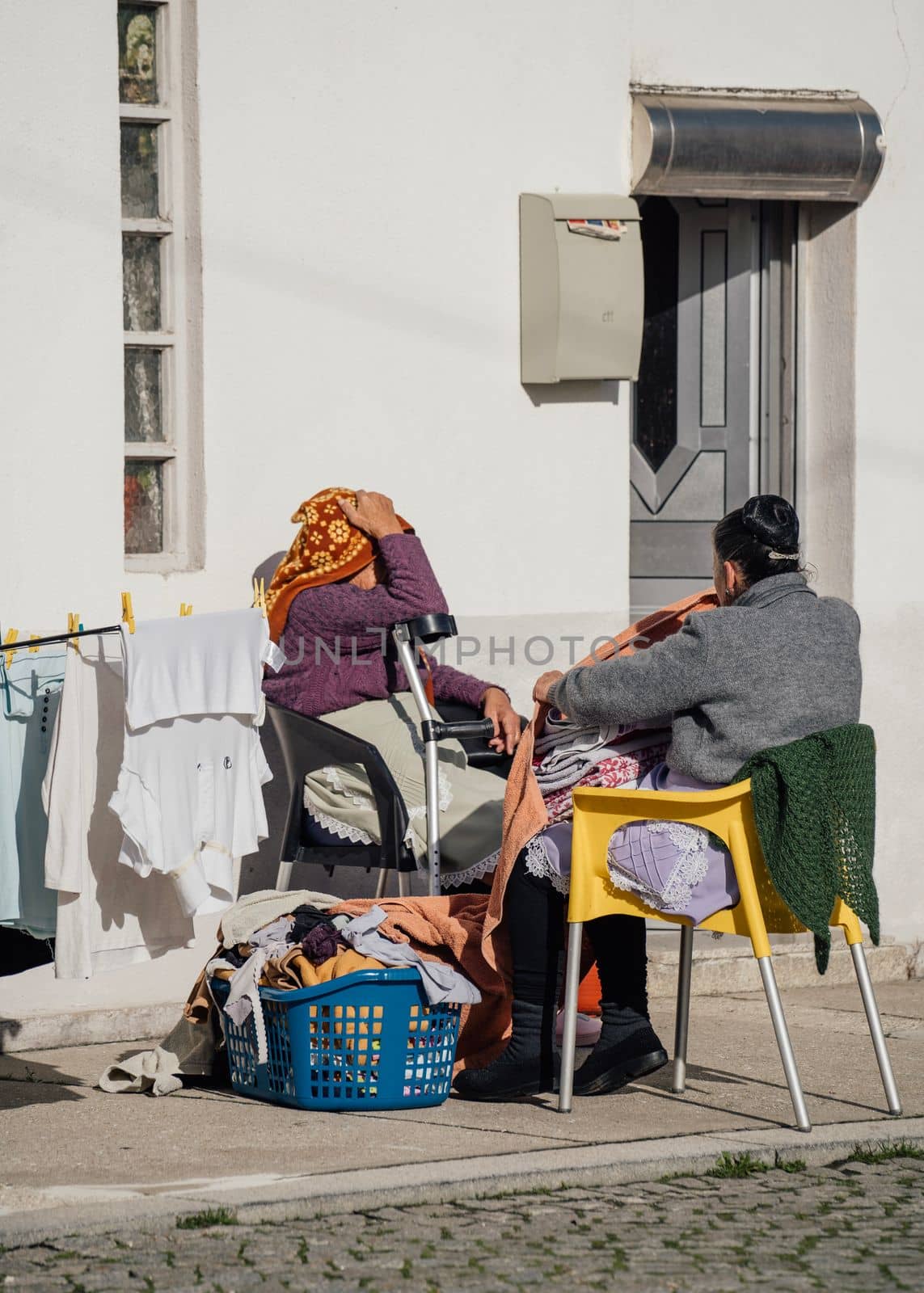 Grandmother or housekepper working with laundry outdoors in a sunny day by papatonic