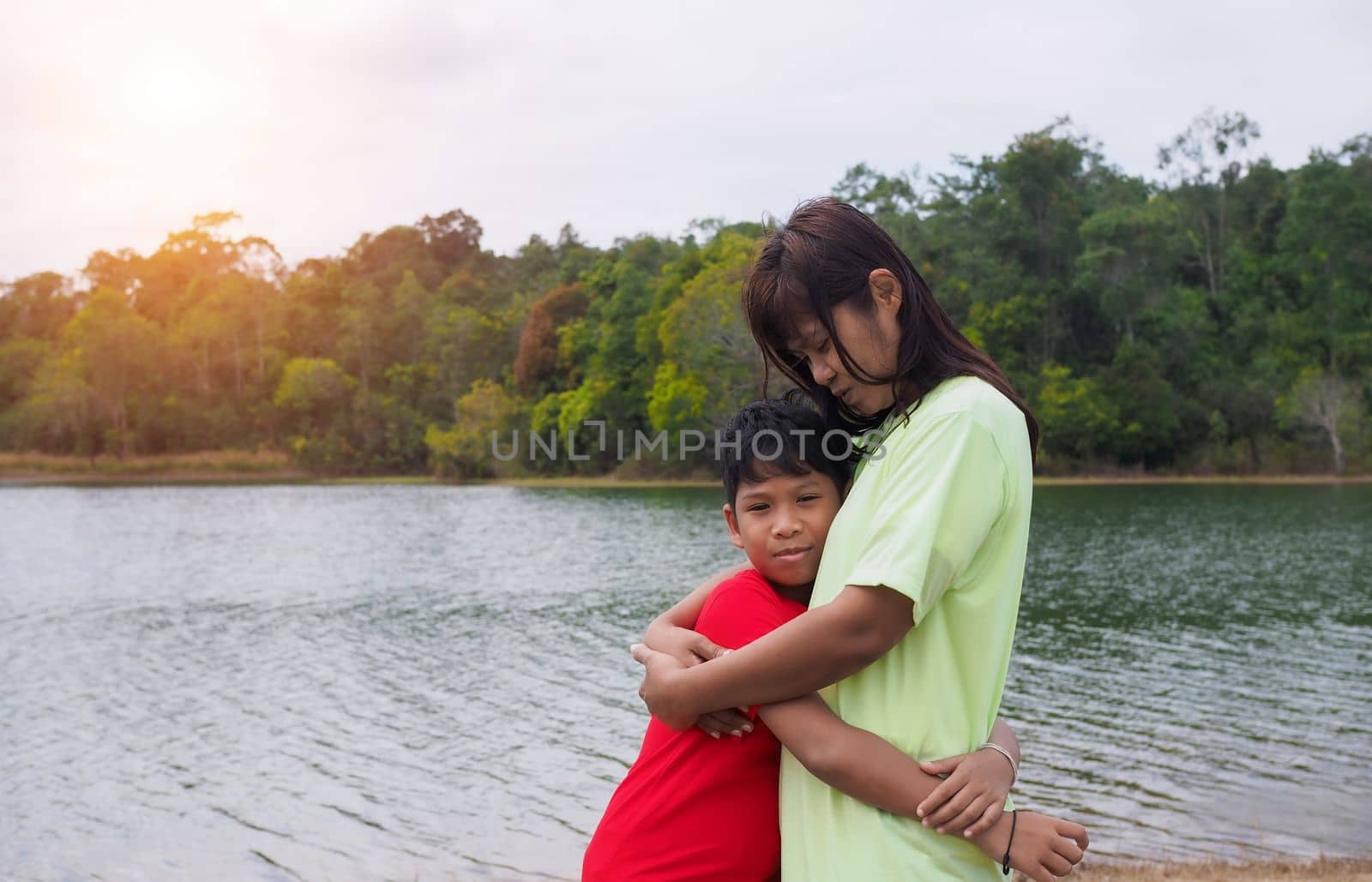 Happy family spending time outdoors hugging and enjoying the view of river. Mother with  kid.