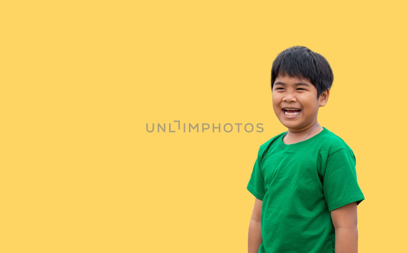 The boy wore a green shirt and stood smiling. on a yellow background by Unimages2527