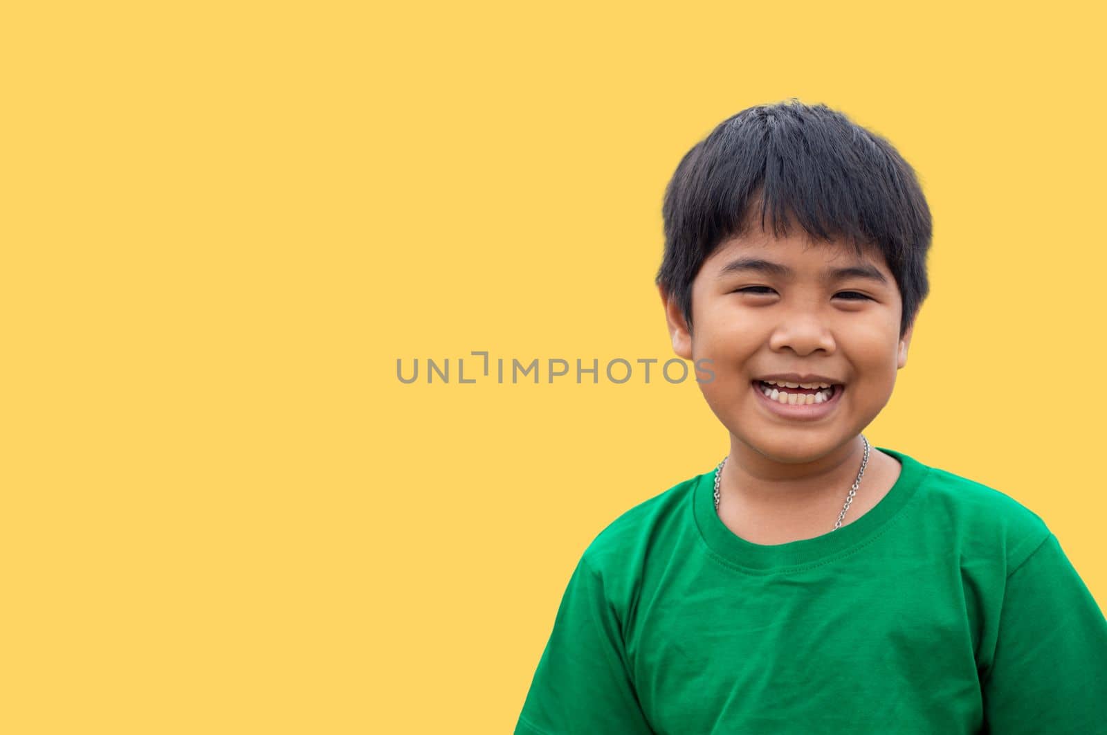 The boy wore a green shirt and stood smiling. on a yellow background