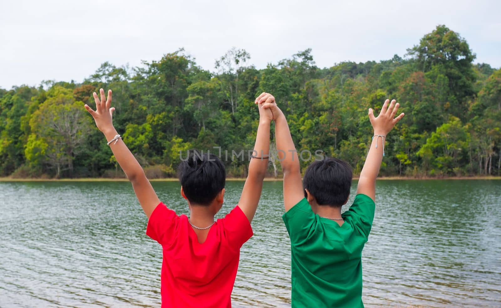 two brothers holding hands Standing on the banks of the reservoir. The concept of family love.