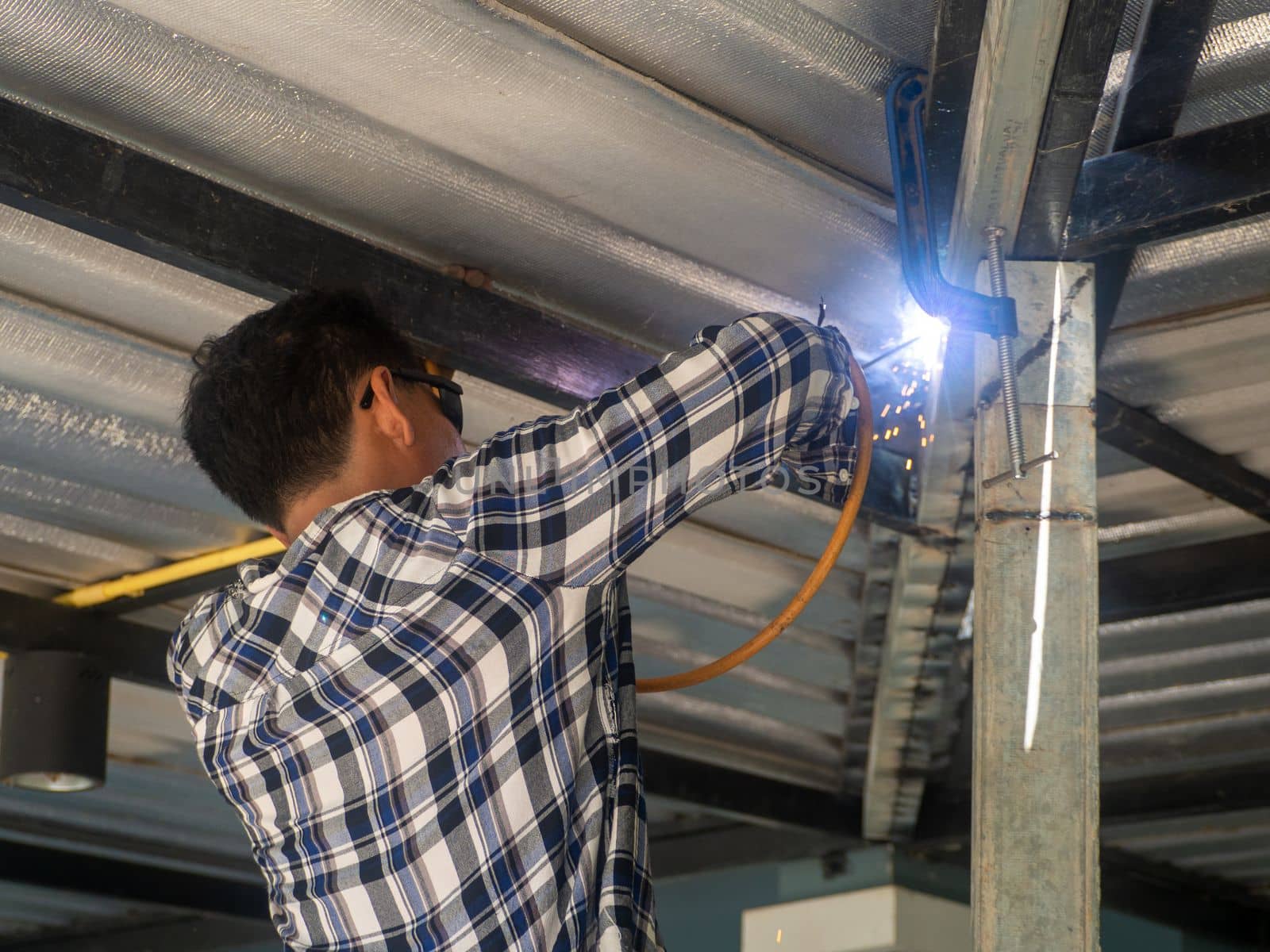 A welder is working on a steel frame. At the construction site.