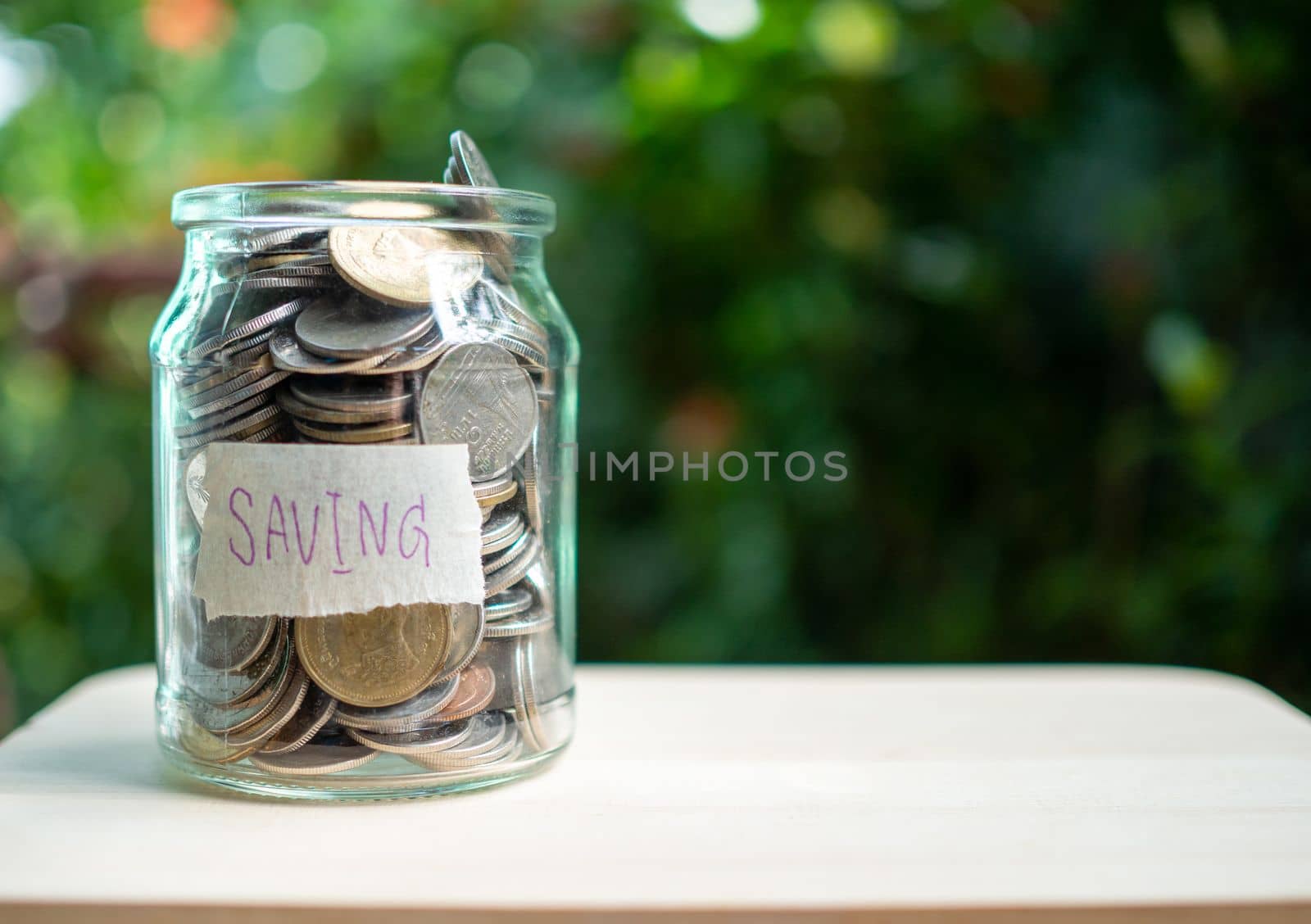 Piggy bank bottle with saving sign on natural bokeh background