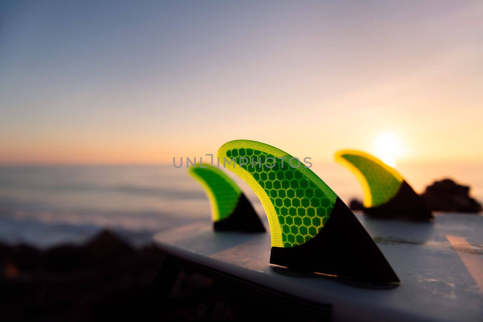 fins of a surfboard on the beach at sunset, leisure and hobbies concept, copy space for text