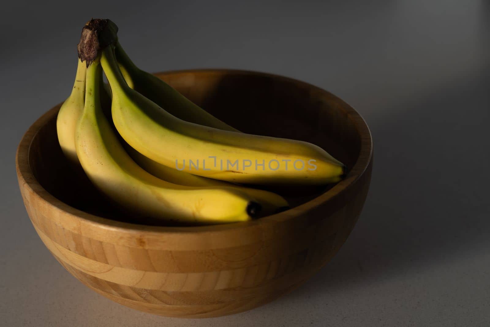 bananas in a wooden bowl with lights and shadows