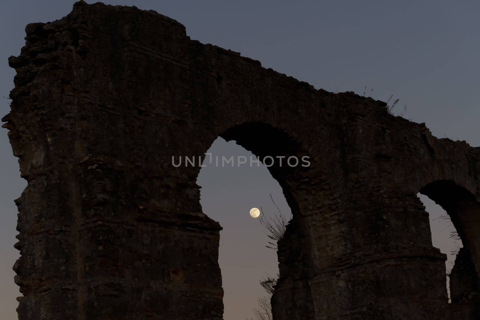 stone arches with full moon in the background at sunset