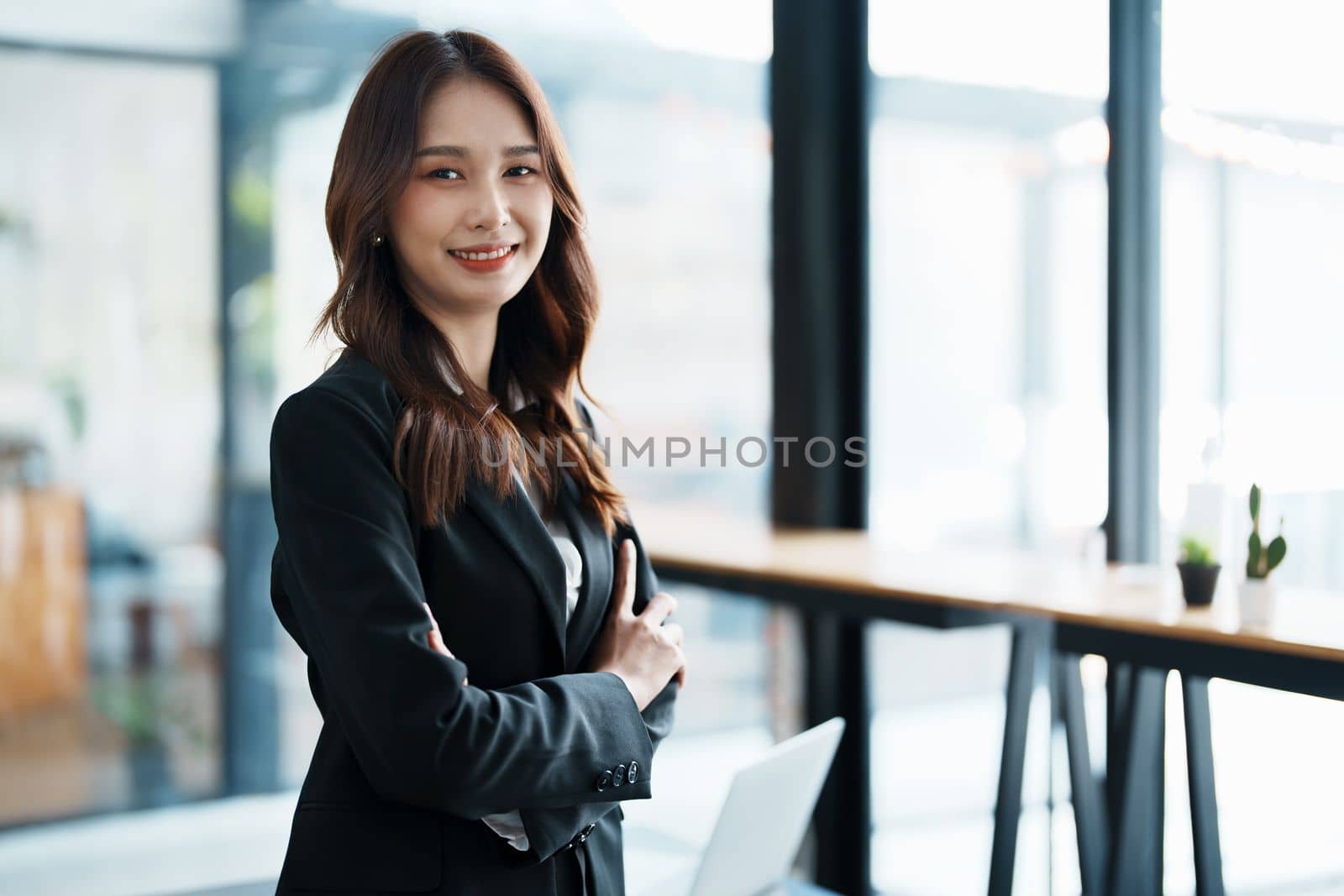 Portrait of a woman business owner showing a happy smiling face as he has successfully invested her business using computers and financial budget documents at work by Manastrong