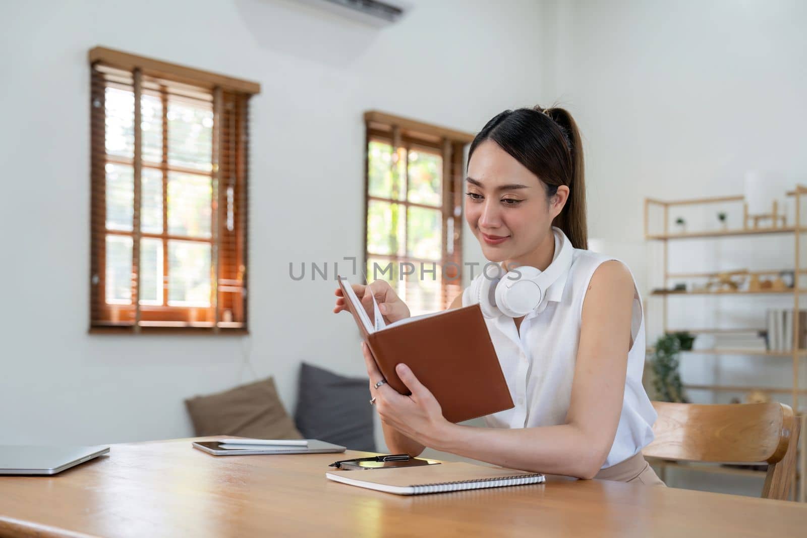 Beautiful young aisna woman reading book at home.