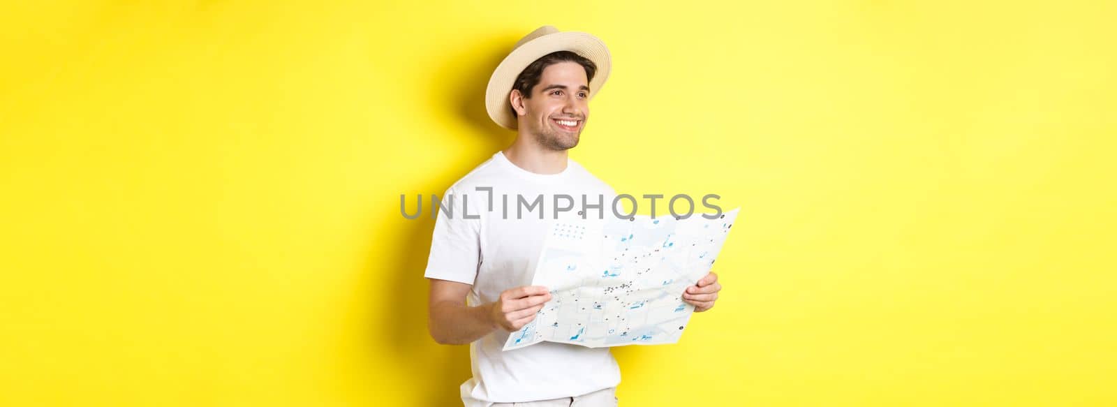 Travelling, vacation and tourism concept. Handsome guy tourist going sightseeing, holding map and smiling, standing over yellow background by Benzoix