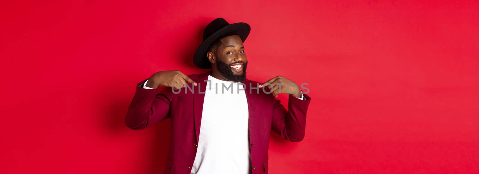 Christmas shopping and people concept. Handsome Black man pointing at himself, going on party, standing confident against red background.