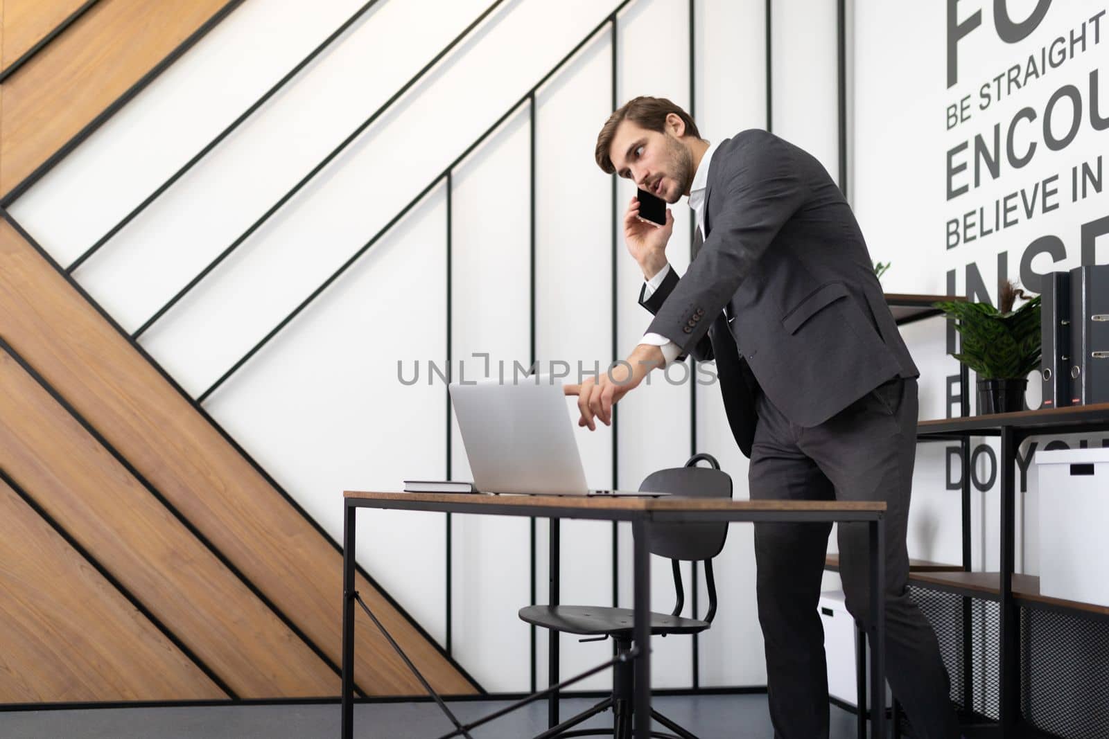 successful businessman talking on the phone at the desktop with a laptop in the office by TRMK