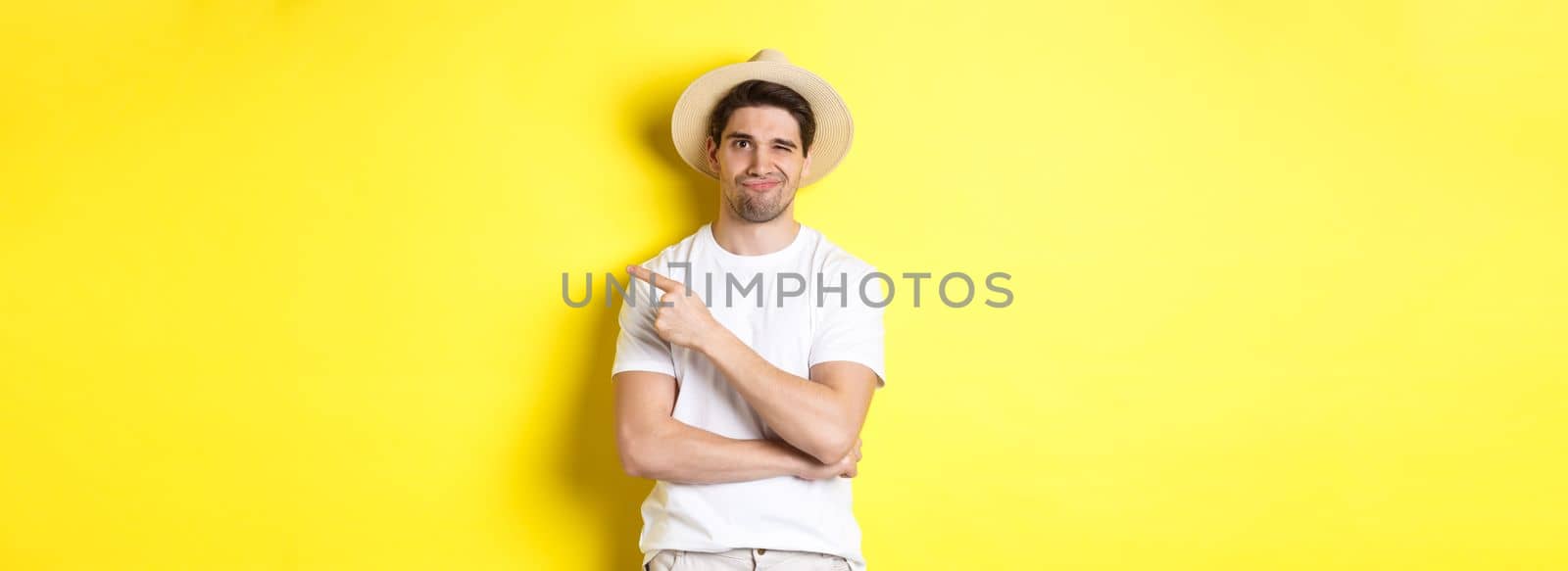 Skeptical male tourist complaining, pointing finger right at something bad or lame, standing unamused against yellow background by Benzoix
