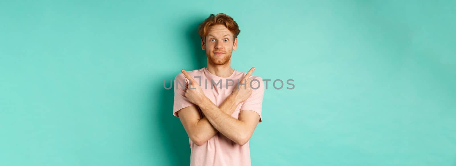 Attractive indecisive man in t-shirt cross hands and pointing sideways, showing two choices, need help with decision, standing over turquoise background.