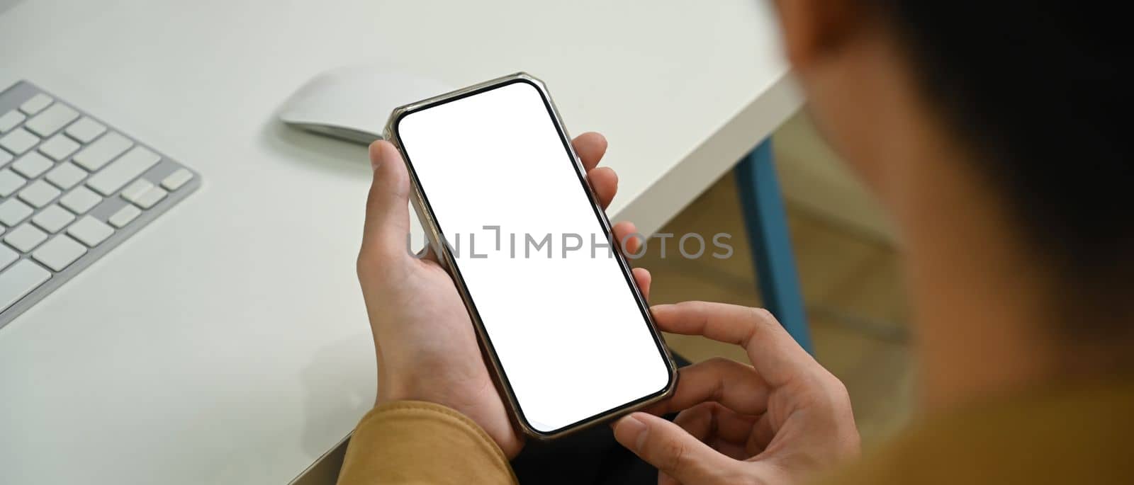 Close up view man holding mock up smart phone with white screen.