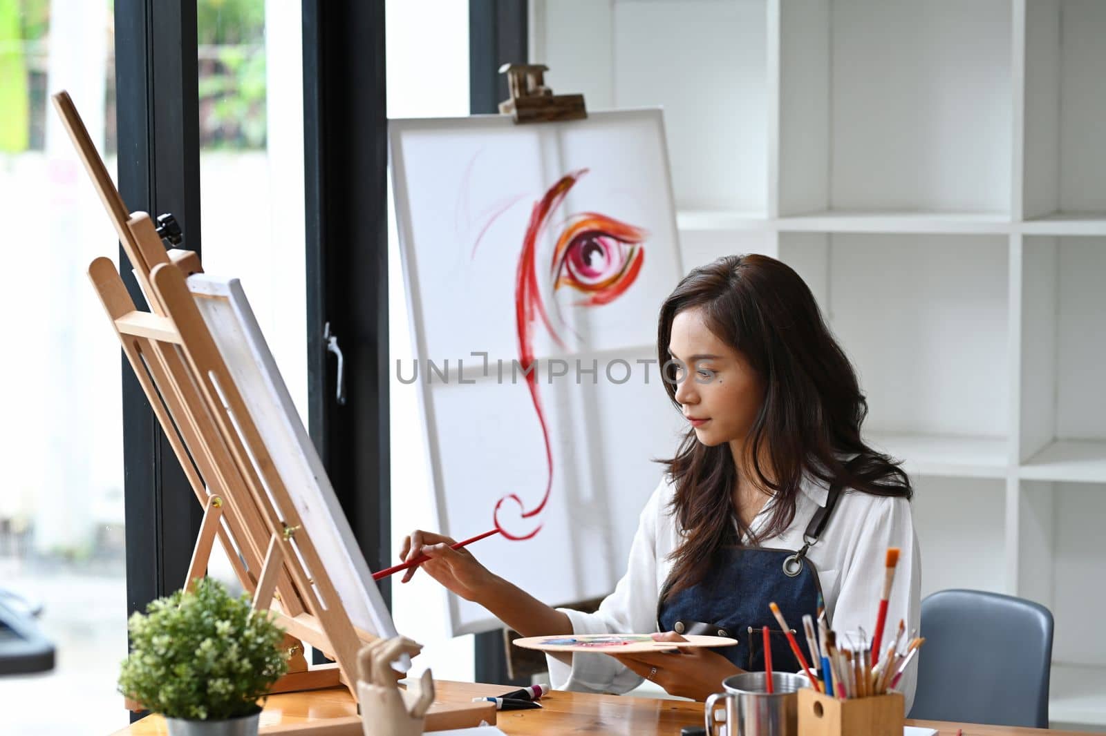 Beautiful Asian woman painting with watercolor at her art workshop. by prathanchorruangsak