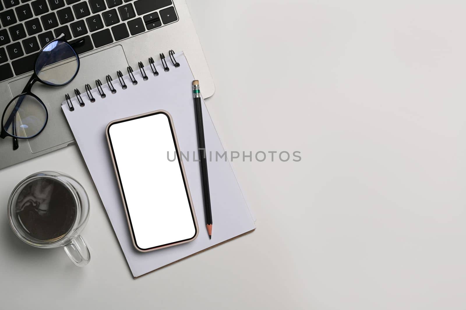 Mock up smart phone, notepad, coffee cup and laptop computer on white office desk. by prathanchorruangsak