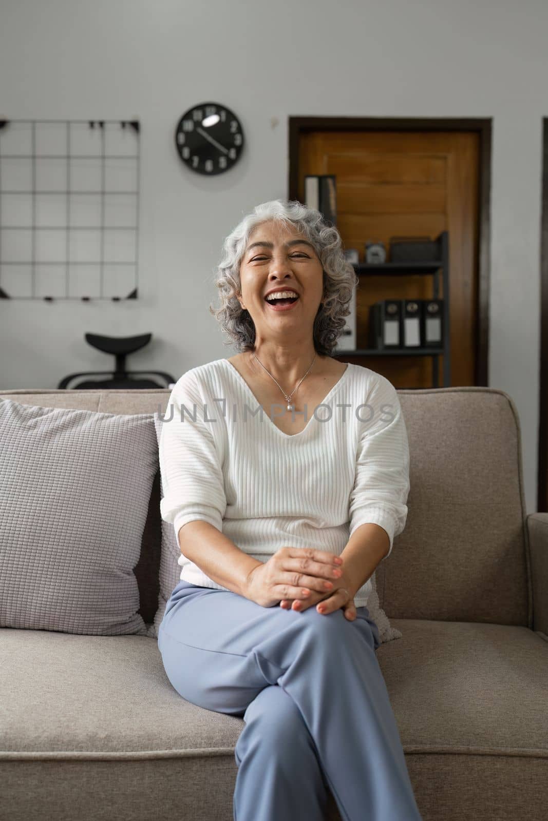 Portrait happy healthy elderly woman sitting on comfortable couch at home. by itchaznong