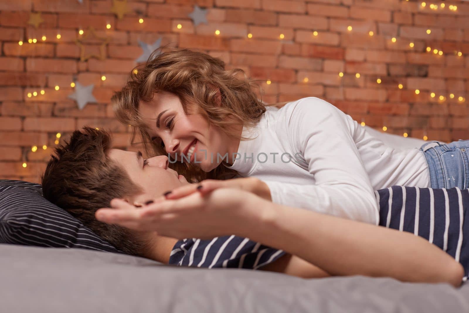 Caucasian young beautiful couple lie on bed and hugging each other by nazarovsergey