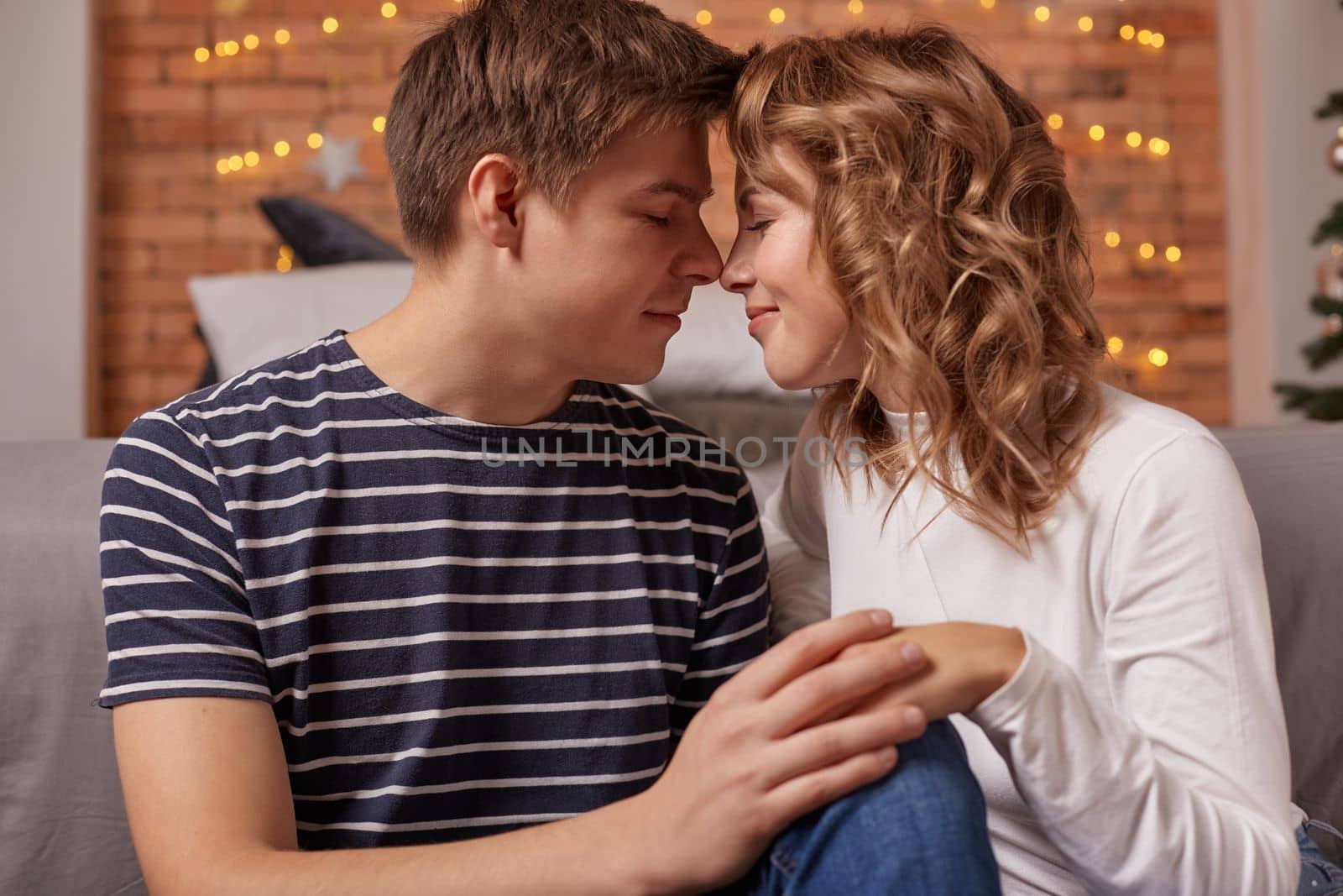 Close up portrait of a beautiful couple sitting on the floor embracing and looking to each other. They are in love and happy