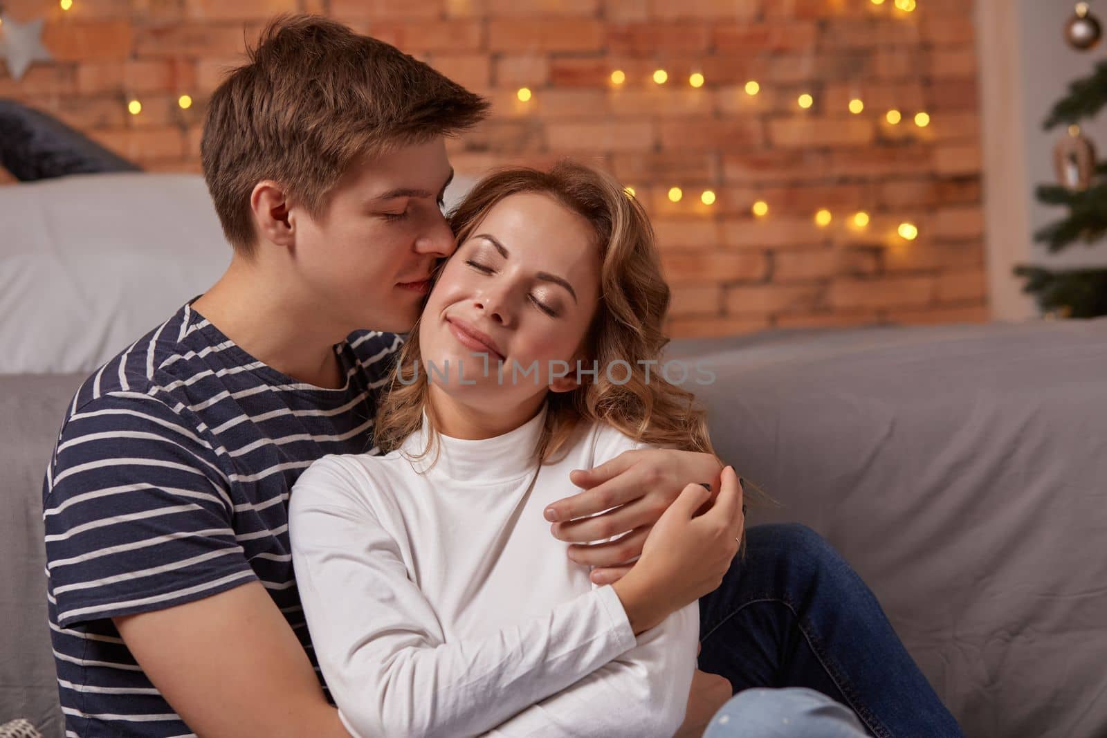 Portrait of a young loving couple resting on a grey couch together at home and hugging. they feel great