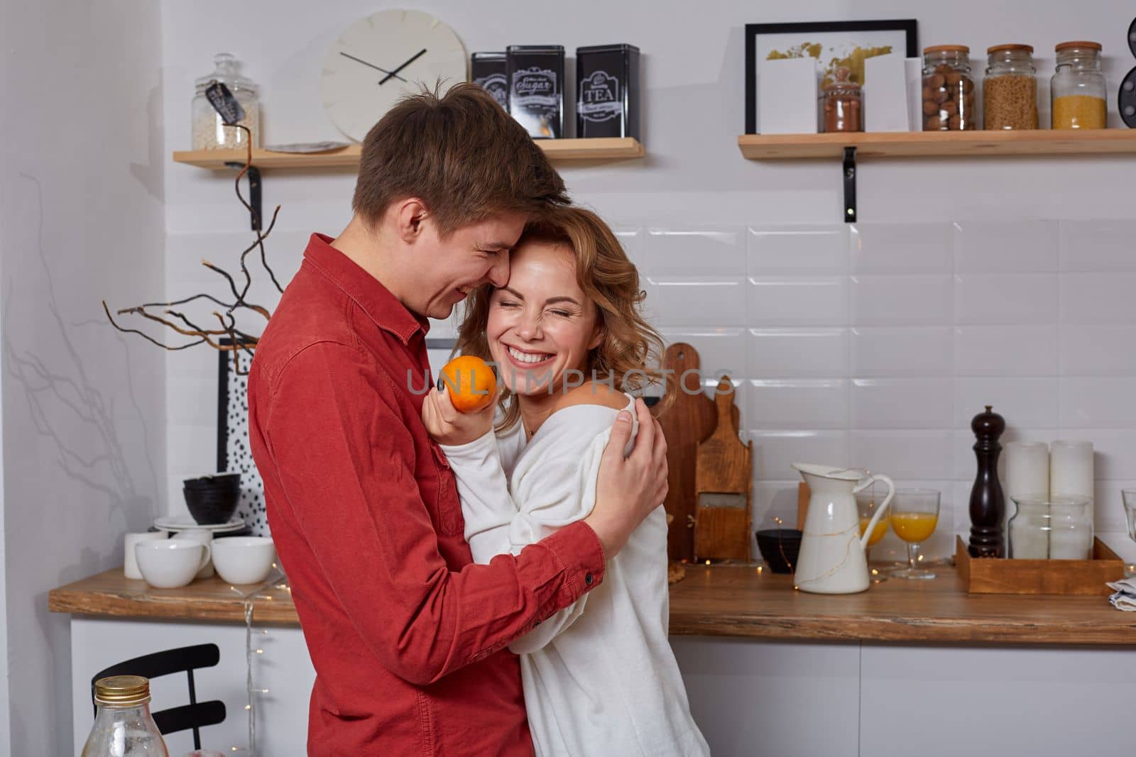 Happy young lovely couple on kitchen hugging each other. They enjoy spending time togehter. They show emotions to each other
