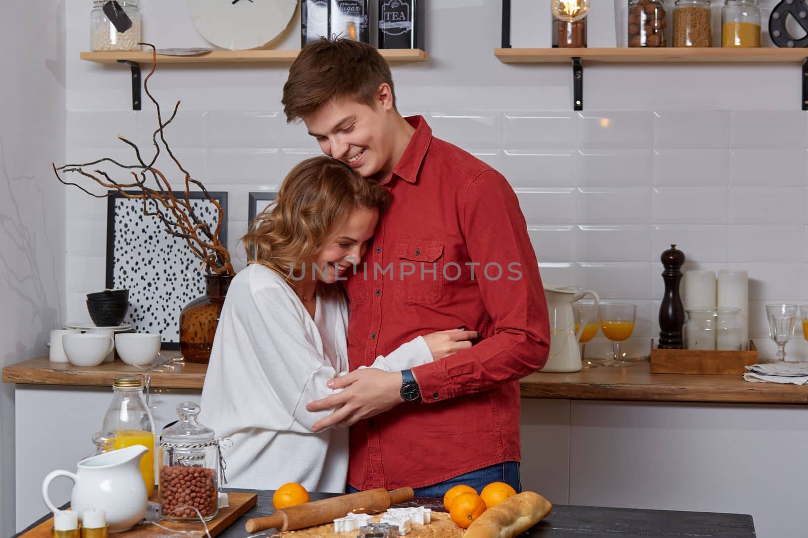 Happy young lovely couple on kitchen hugging each other. They enjoy spending time togehter. Happy couple fooling around