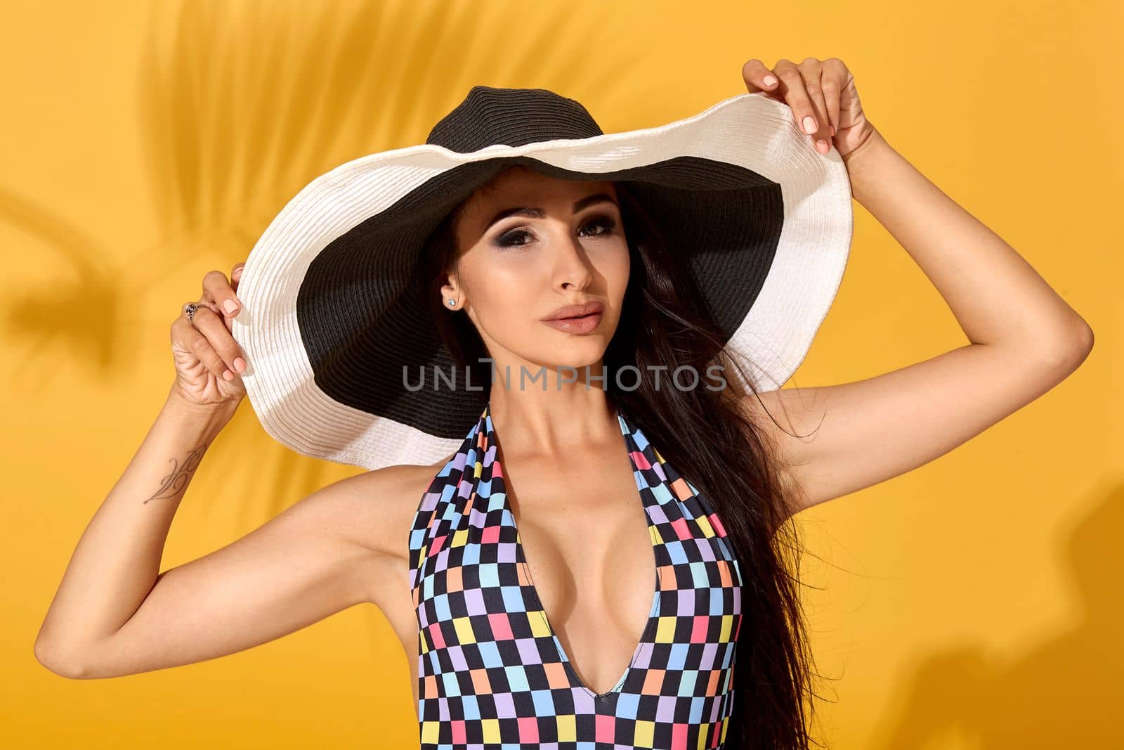 Young sexy confident brunette woman posing before camera, wearing bikini and big nice black hat by nazarovsergey