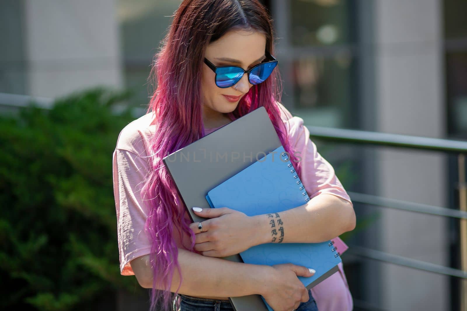 Portrait beautiful female writer dressed in casual outfit holding modern laptop in hand. Young student of faculty journalism having good mood outdoor