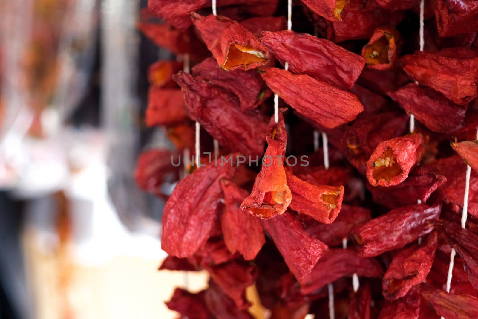 Dried paprika pepper pieces hanging on threads for sell, selective focus