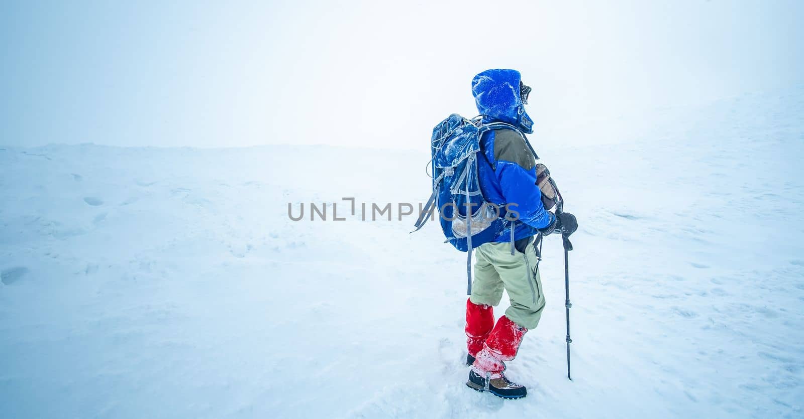 Well equipped hiker standing on top of snowy winter mountain