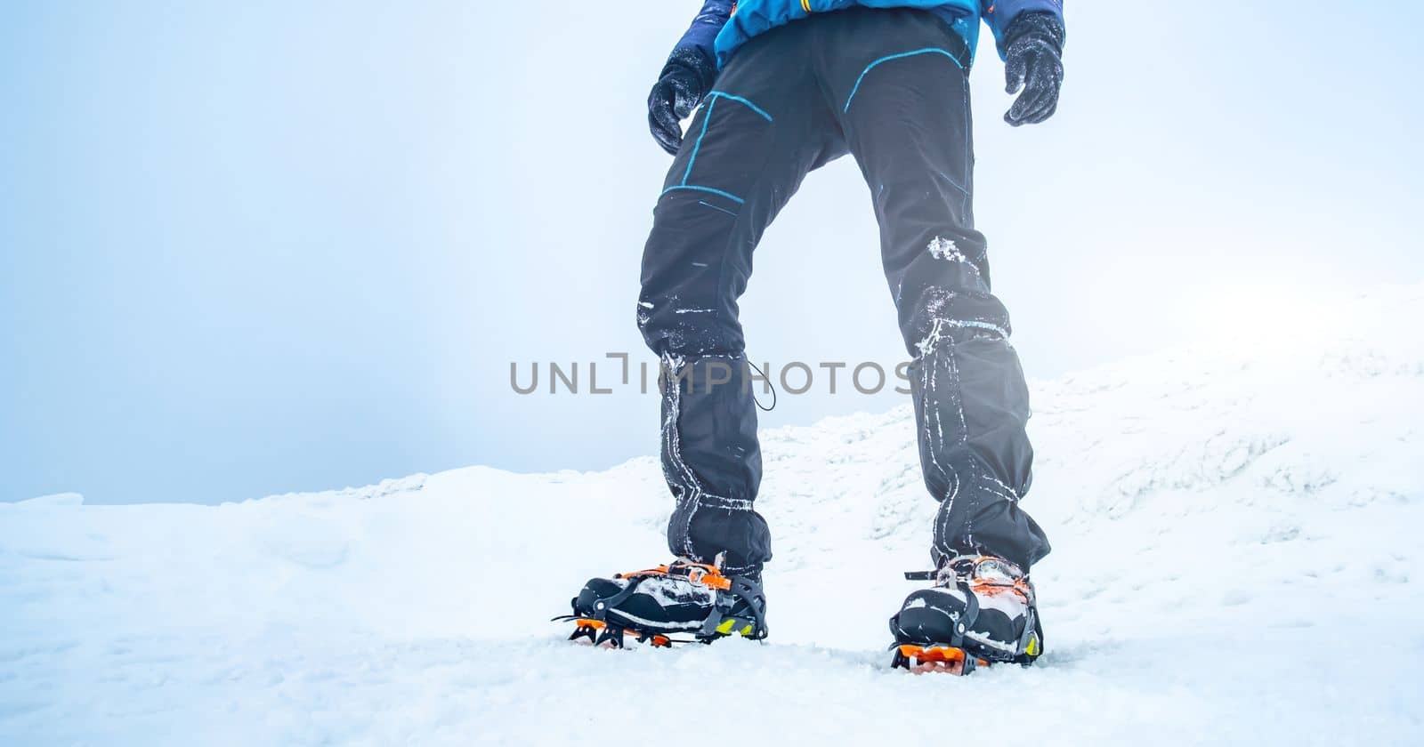 Man trekking snowy mountain using crampons for deep snow
