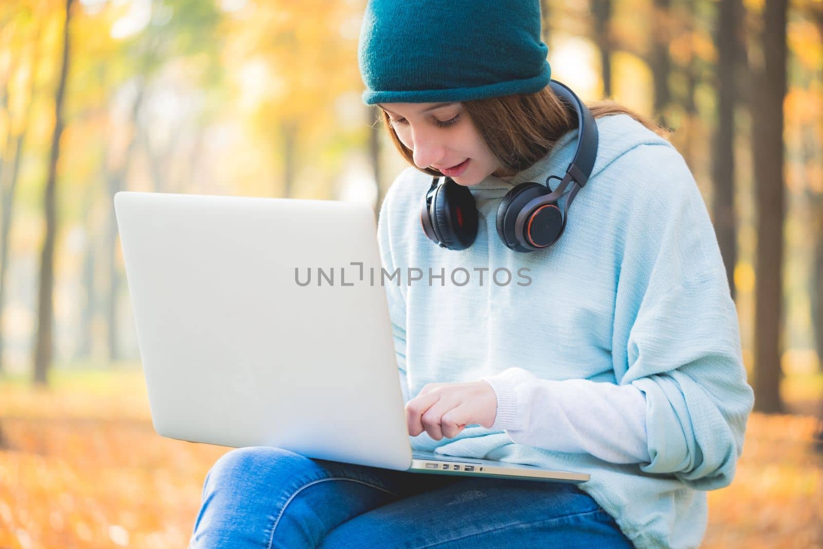 Smiling teenage girl sitting on bench with laptop
