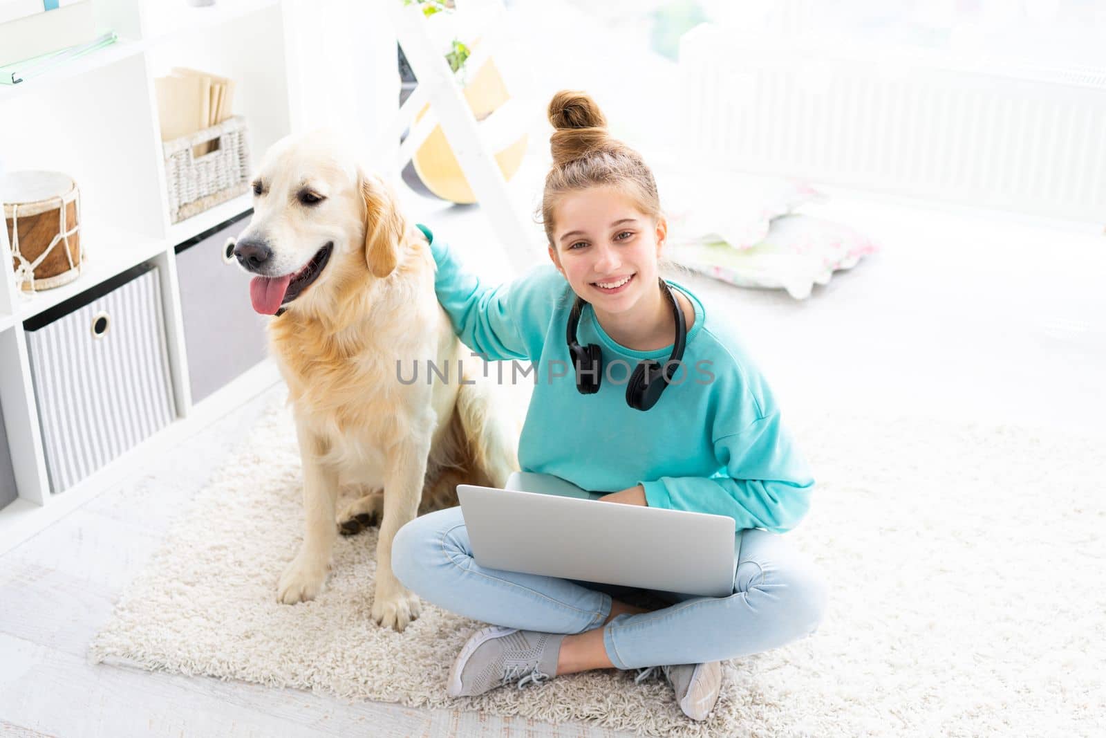 girl with pretty dog working on laptop in bright room, top view