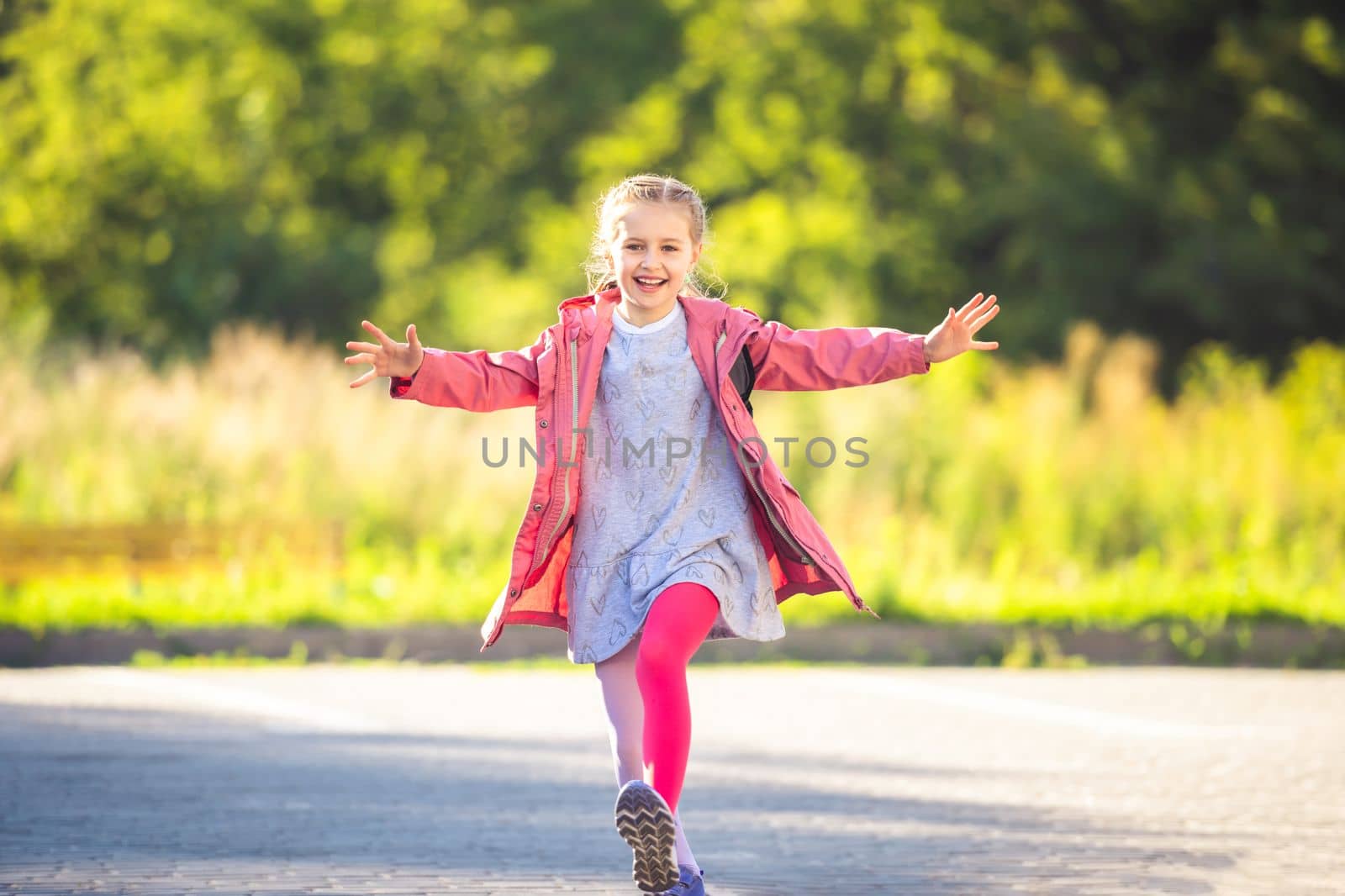 Happy little girl running with open arms on car parking after school