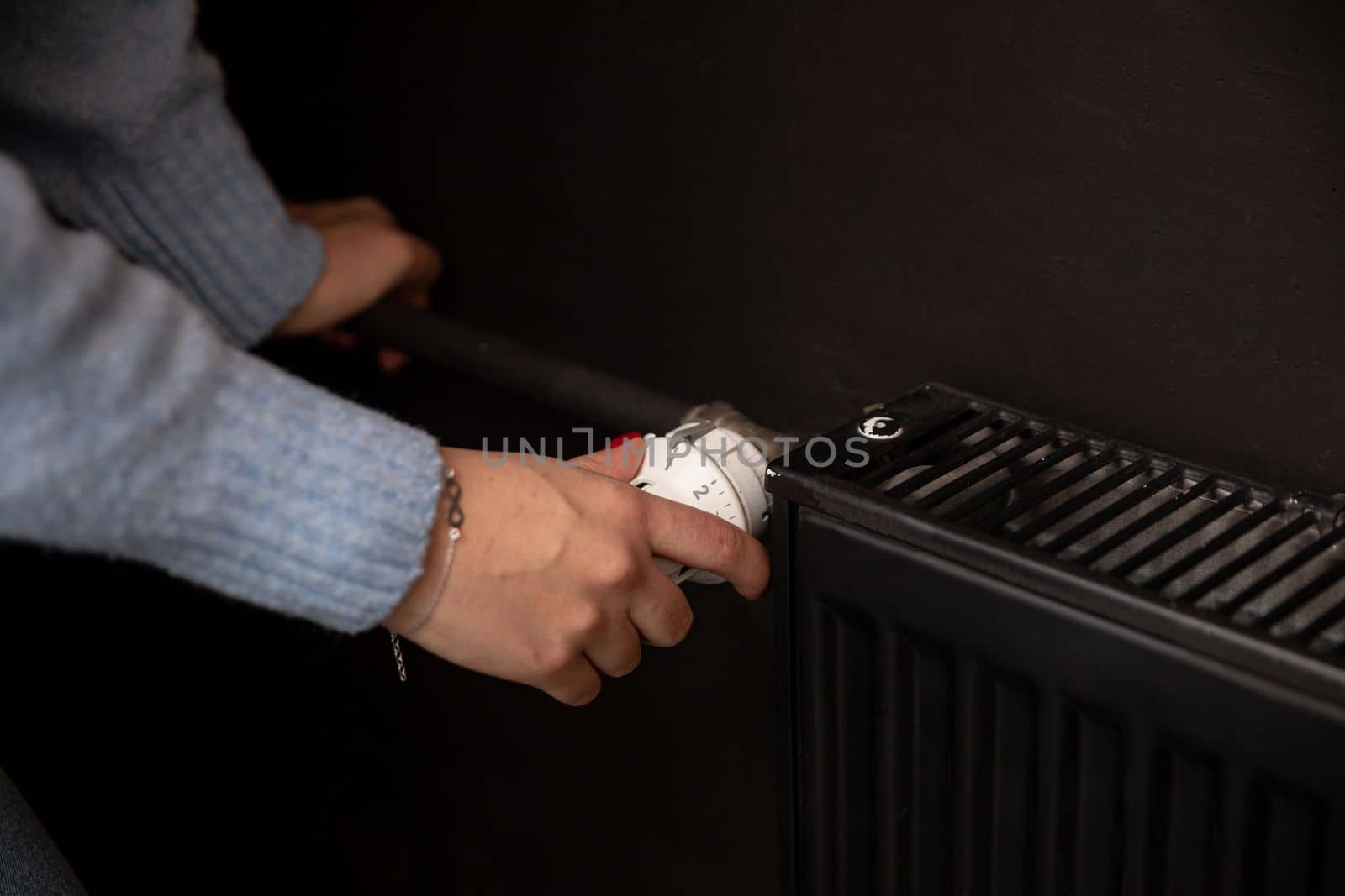 Turning up the heat in a radiator on cold days. Black panel radiator. Central heating in your own home.