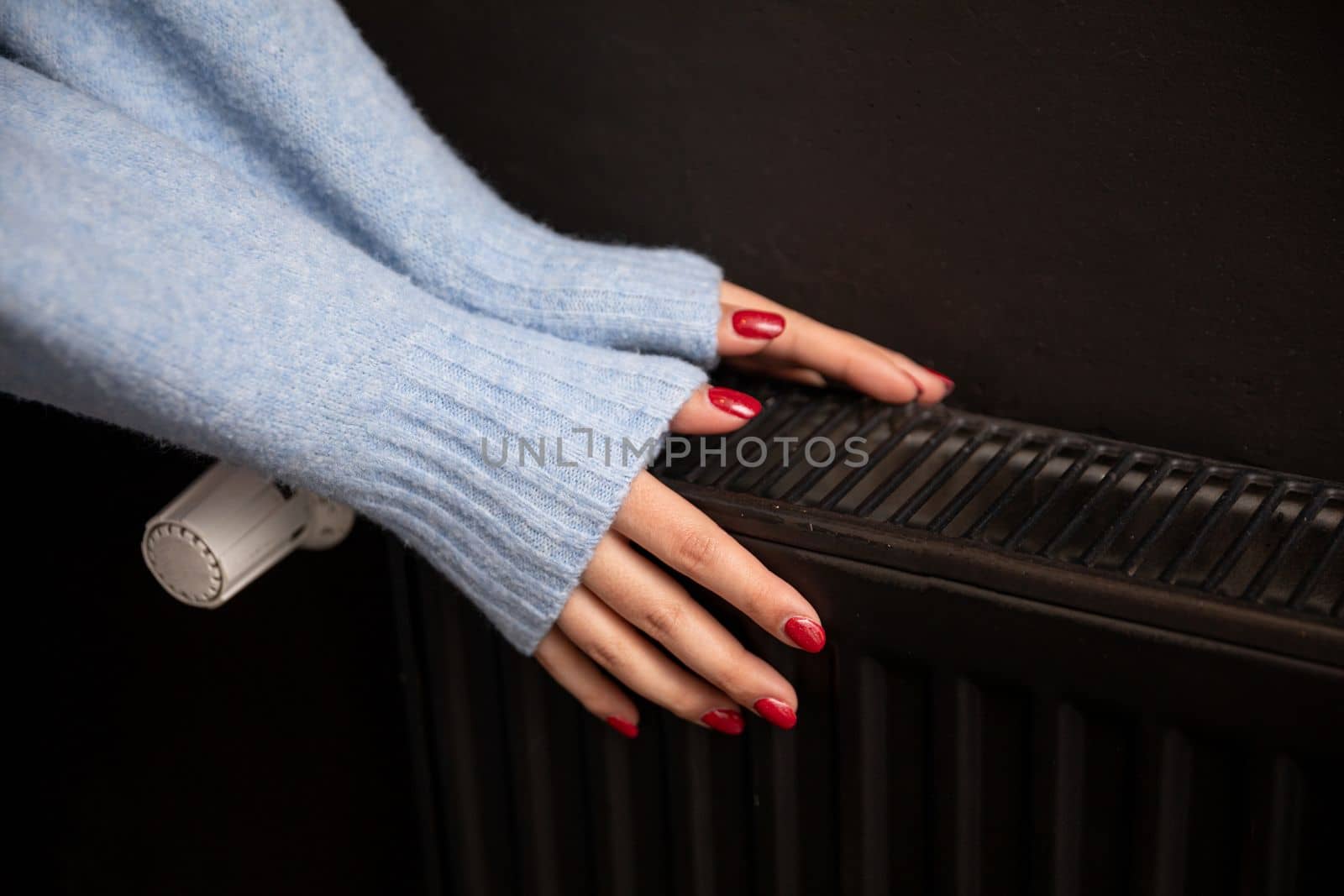 Women's hands touch the radiator to get warm. Central heating essential in winter. Thermal energy in the home.