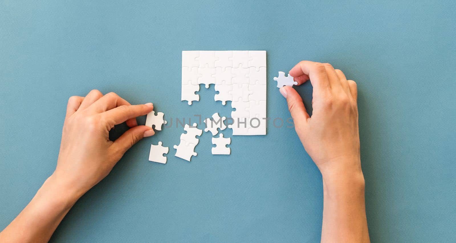 Hands with Small white square puzzle on a blue background