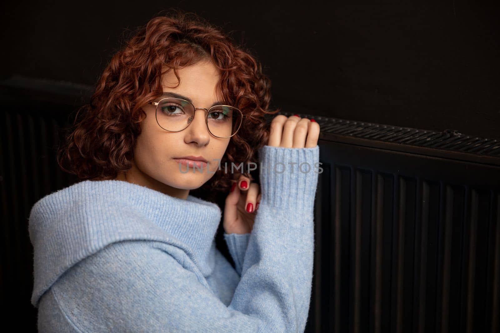 During the winter season and poor heating, the girl hugs the radiator. Central heating necessary in the house during the winter period.