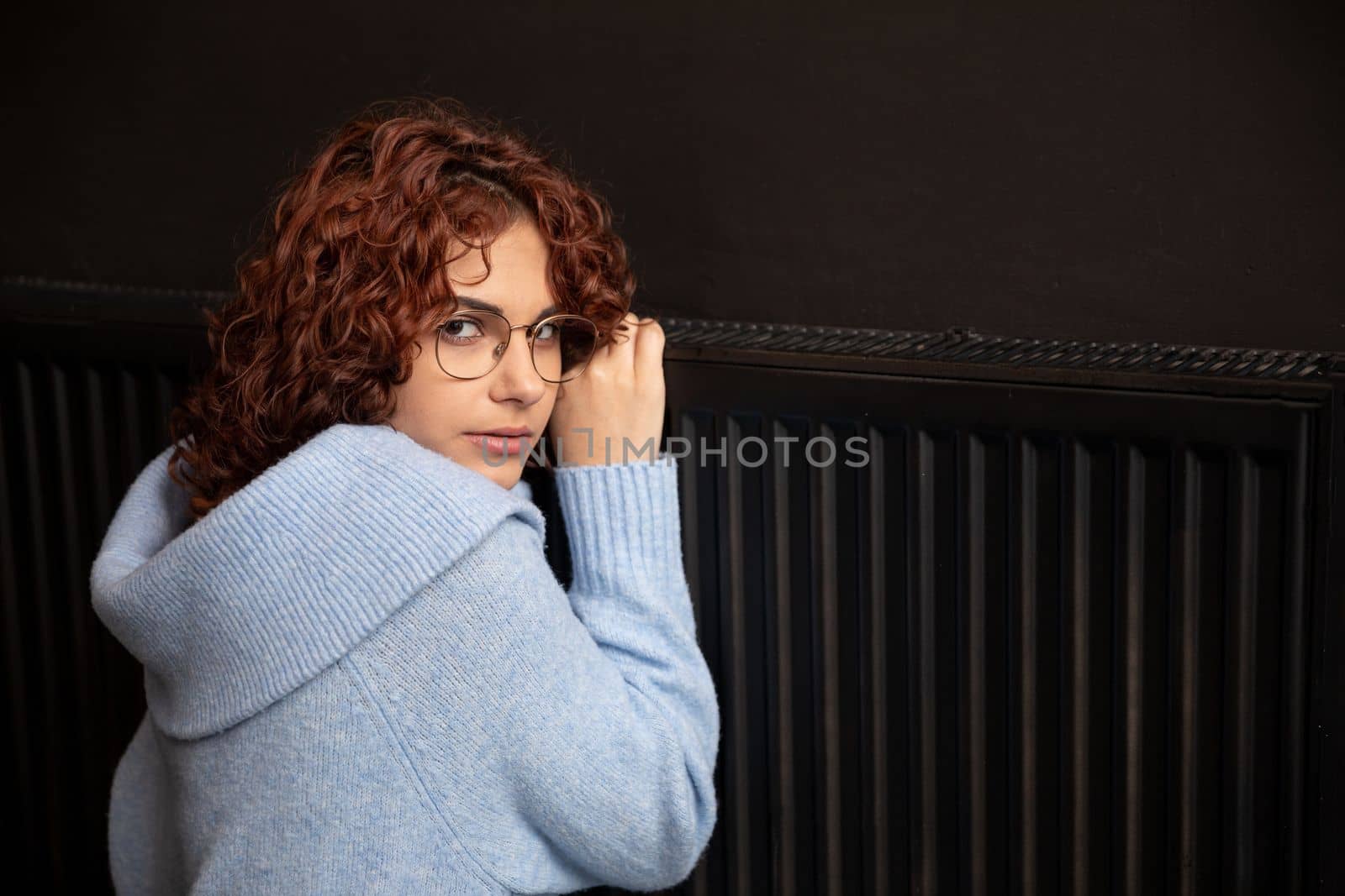During the winter season and poor heating, the girl hugs the radiator. Central heating necessary in the house during the winter period.