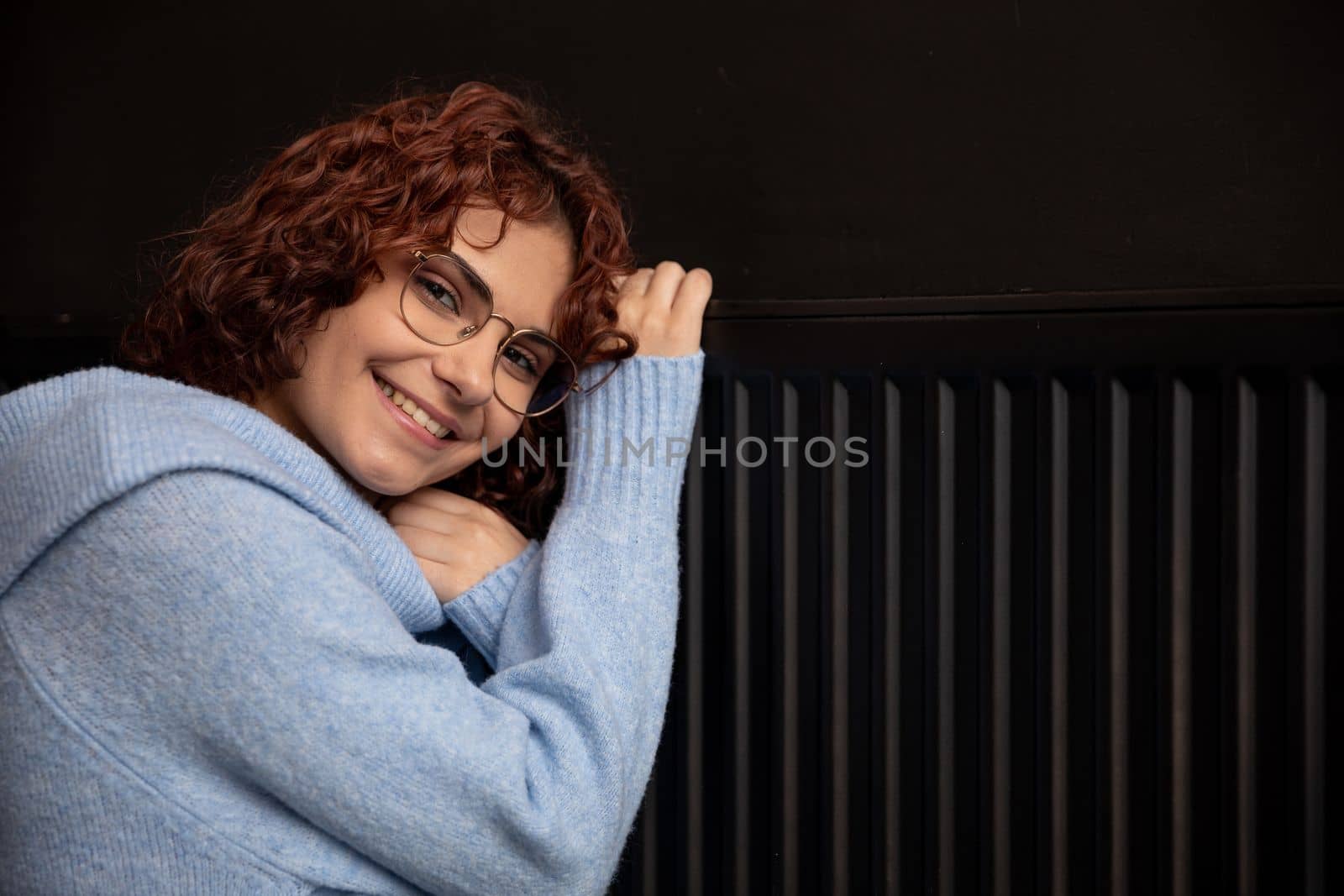 Satisfied girl. Warming up by the hot radiator. Efficient central heating at home. The winter period is the time for space heating.