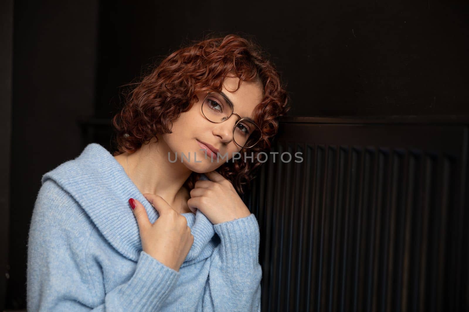 The girl waits by the radiator until the heat appears. The winter period is the time for space heating. Sad and cold if there is a lack of central heating.