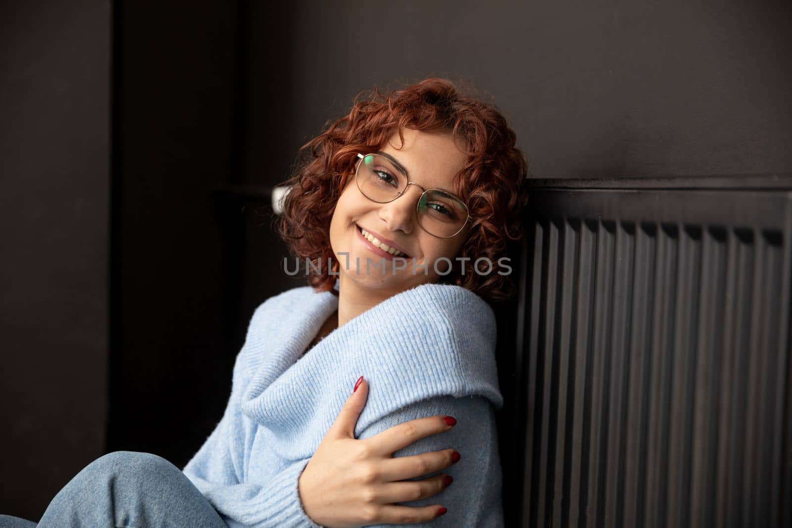 Satisfied girl. Warming up by the hot radiator. Efficient central heating at home. The winter period is the time for space heating.