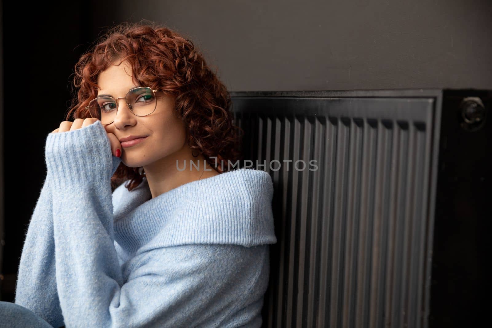 In the winter period when the room is chilly and the radiators heat poorly then the girl likes to sit close to the radiator. The winter period is the time to heat the room.