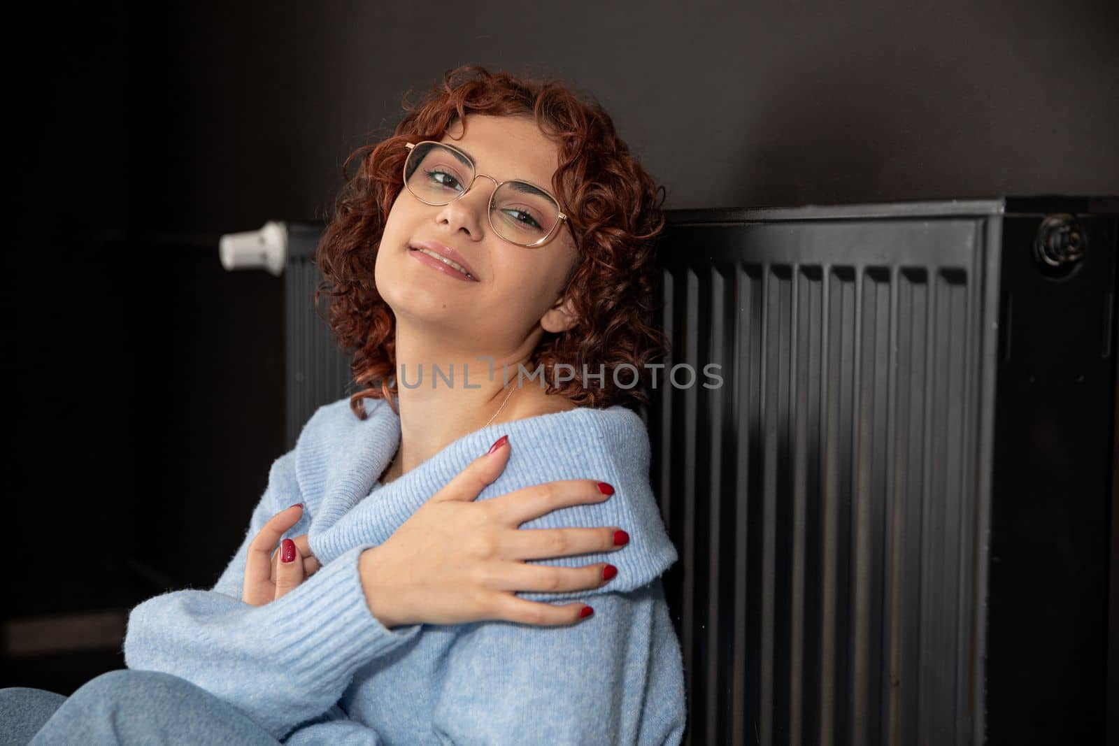 In the winter period when the room is chilly and the radiators heat poorly then the girl likes to sit close to the radiator. The winter period is the time to heat the room.