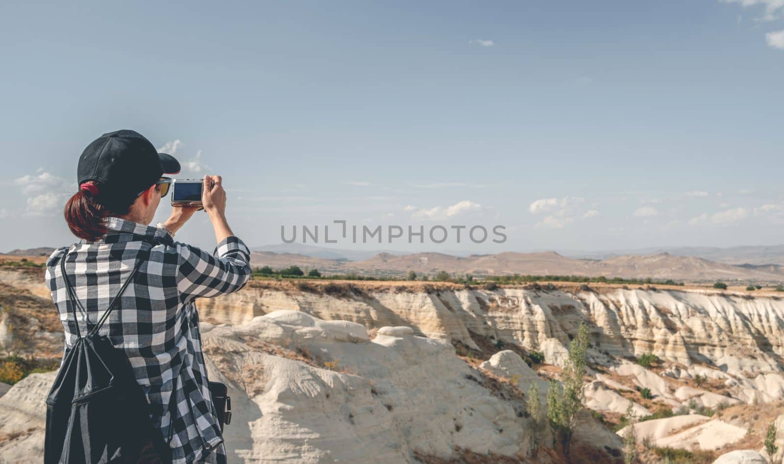 Rear view of woman tourist photographing canyon in Cappadocia, Turkey