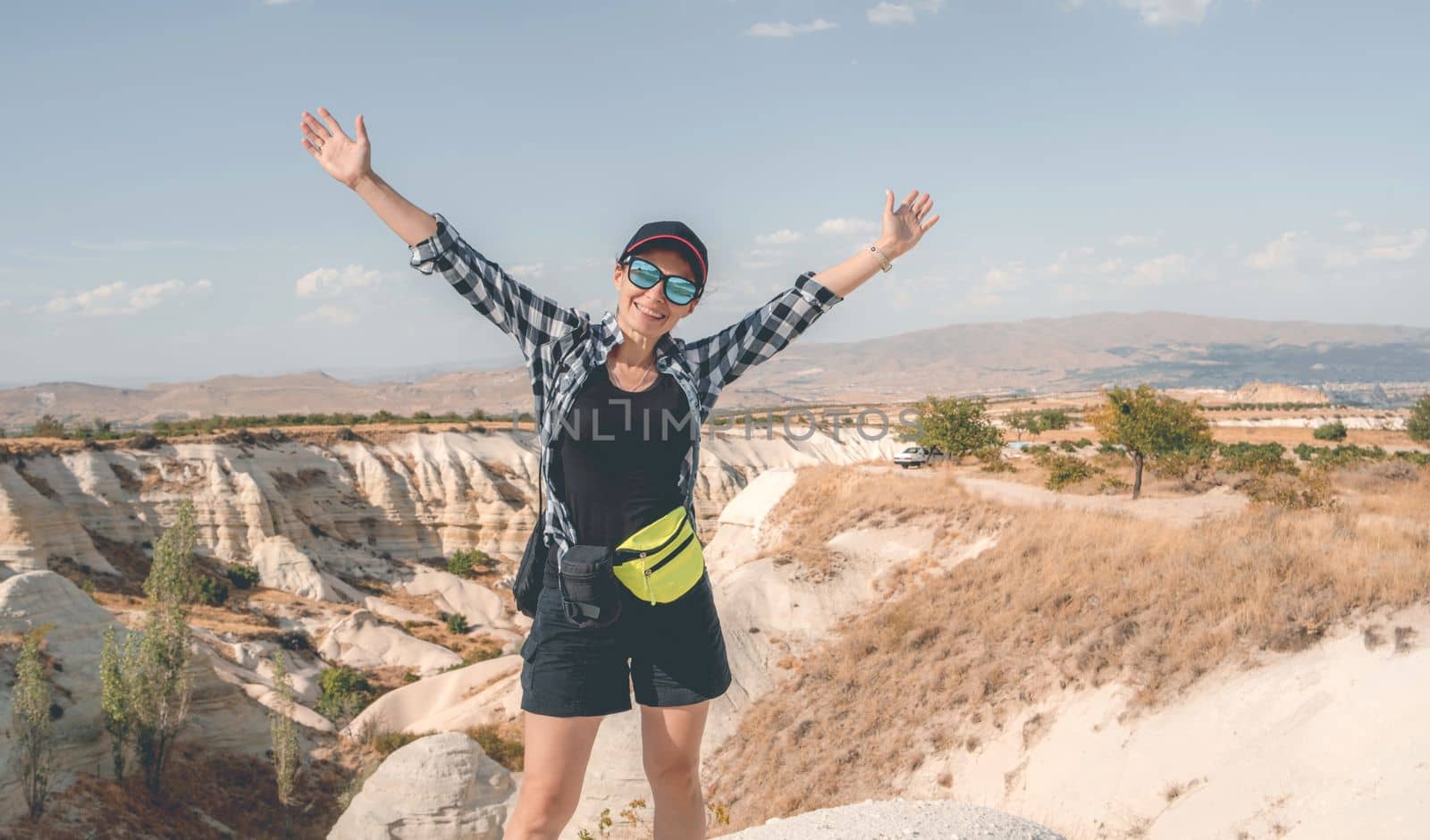 Tourist standing with raised hands on canyon in Cappadocia background, Turkey