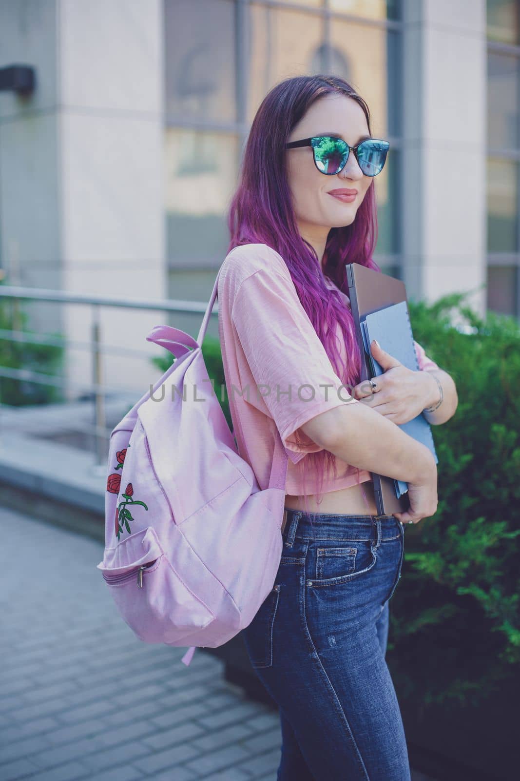 Portrait beautiful female writer dressed in casual outfit holding modern laptop in hand with backpack. Young student of faculty journalism having good mood outdoor