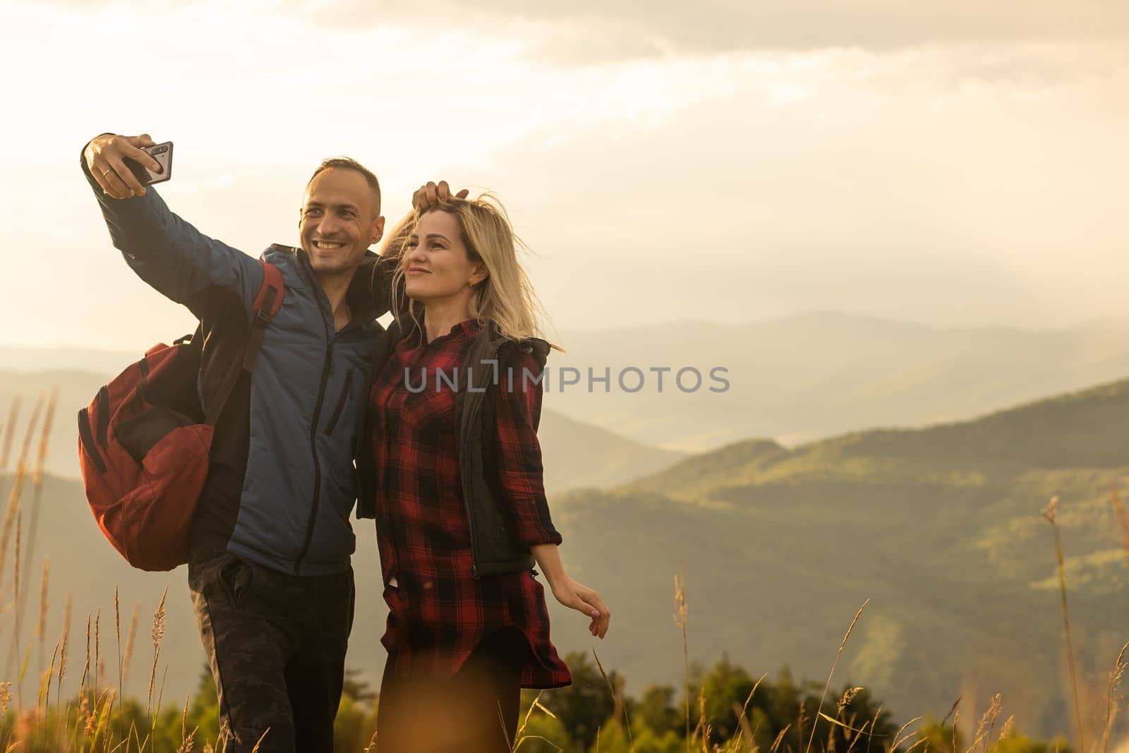 travel to mountains, tourists hikers with backpacks at sunset enjoying panoramic view.