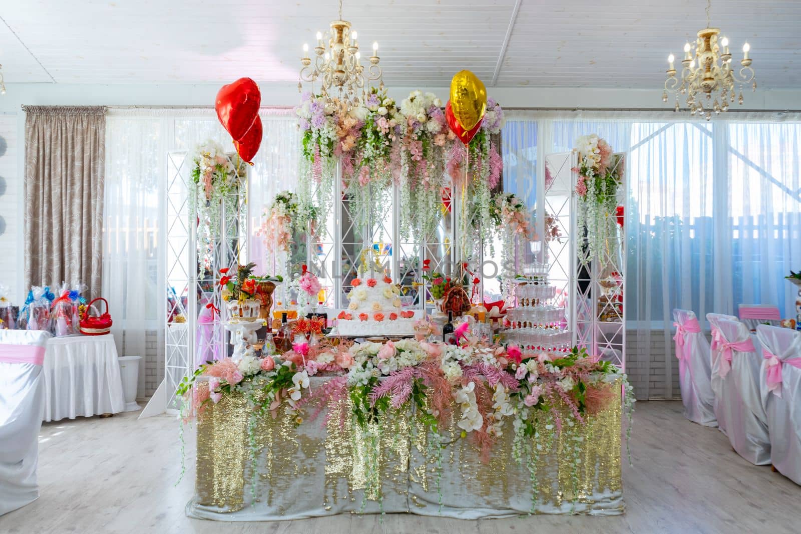 The wedding table of the bride and groom is decorated with many different flowers. A big cake on the bride's table. Ukraine, Vinnytsia, August 10, 2021 by Serhii_Voroshchuk